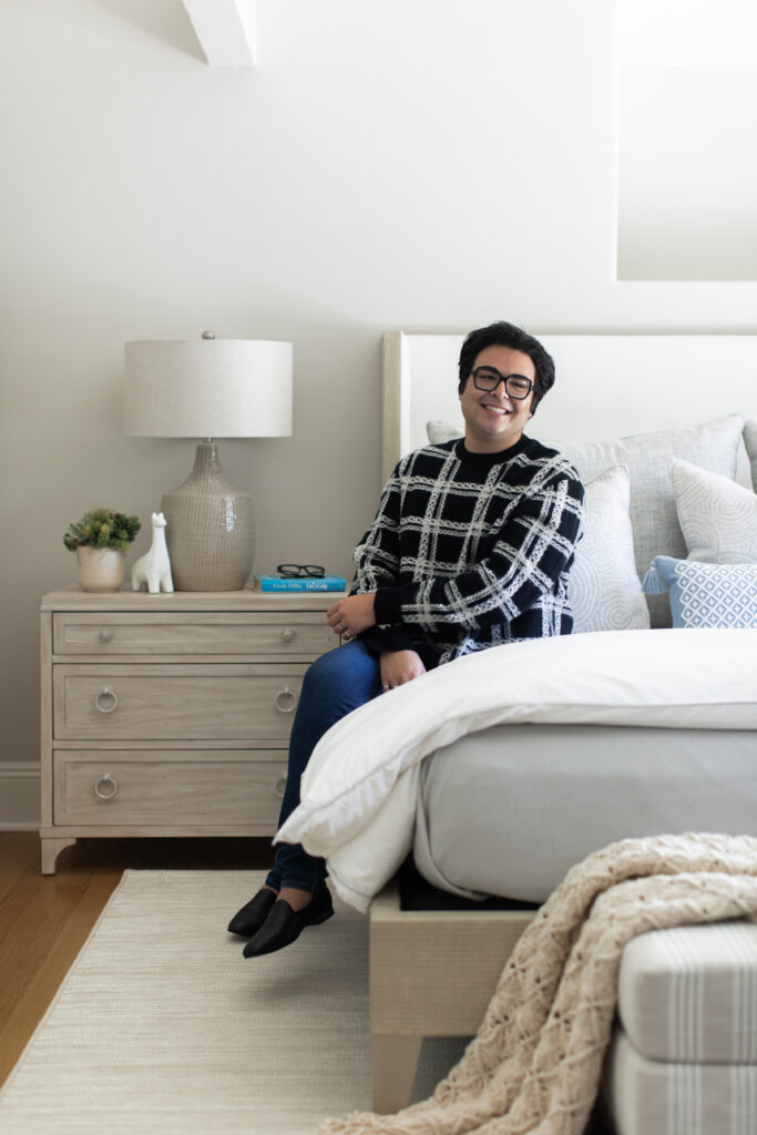 Ethan Charles sitting on a white bed set in a peaceful bedroom decoration