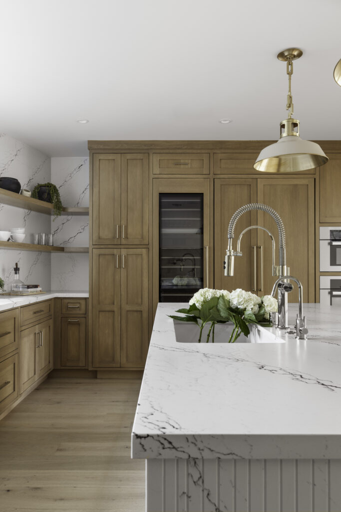 Luxury kitchen design featuring cabinets, marble countertops, and brass pendant lighting